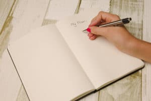 Female hand holding a pen and writing a plan in a planner for planning a digital job ad.